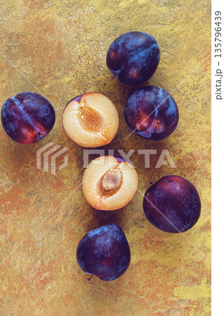 plums scattered on the table, fresh, top view, yellow-orange background, no people, 135796439