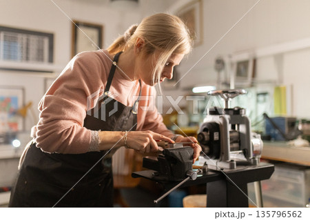 Woman artisan crafting metal in jewelry workshop Woman artisan crafting metal in jewelry workshop 135796562