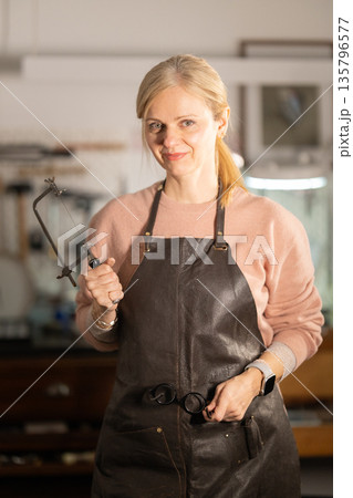 Woman holding jeweler's saw working in workshop Woman holding jeweler's saw working in workshop 135796577
