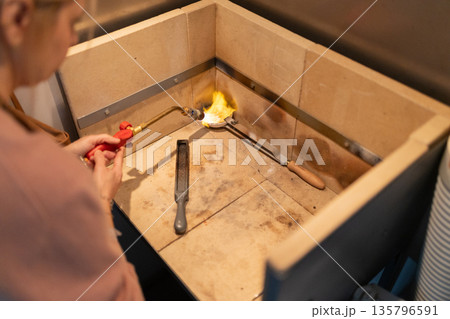 Artisan melting metal with torch for jewelry casting 135796591