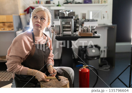 Female artisan creating jewelry in workshop looking up 135796604