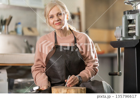 Woman jeweler artisan smiling while crafting in workshop Woman jeweler artisan smiling while crafting in workshop 135796617