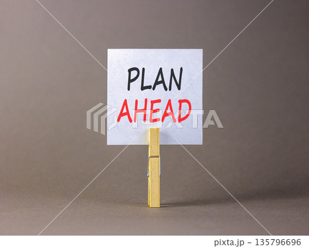 Plan ahead symbol. Concept word Plan ahead on beautiful white paper. Beautiful wooden clothespin. Beautiful grey background. Business plan ahead concept. Copy space. Plan ahead symbol. Concept word Plan ahead on beautiful white paper. Beautiful wooden clothespin. Beautiful grey background. Business plan ahead concept. Copy space. 135796696