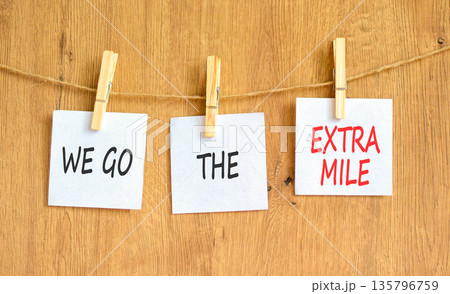 Support, help we go the extra mile symbol. Concept words We go the extra mile on beautiful white papers on clothespin. Beautiful wooden background. Business we go the extra mile concept. Copy space. Support, help we go the extra mile symbol. Concept words We go the extra mile on beautiful white papers on clothespin. Beautiful wooden background. Business we go the extra mile concept. Copy space. 135796759