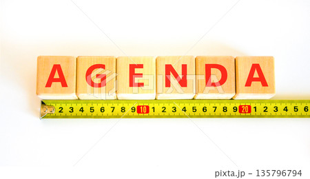 Agenda symbol. Concept word Agenda on beautiful wooden blocks. Beautiful white background. Beautiful yellow tape measure ruler. Business agenda concept. Copy space. 135796794