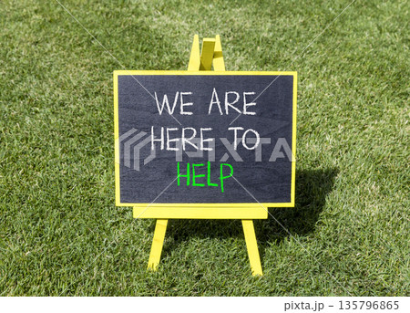 Support, help and we are here to help symbol. Concept words We are here to help on beautiful blackboard. Beautiful green grass lawn background. Business we are here to help concept. Copy space. 135796865