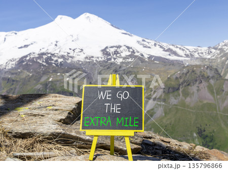 Support, help we go the extra mile symbol. Concept words We go the extra mile on beautiful blackboard. Beautiful mountain Elbrus background. Business we go the extra mile concept. Copy space. 135796866