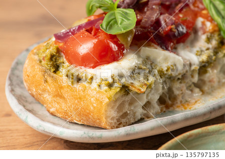Delicious bruschetta with pesto, tomatoes, mozzarella and red onions resting on a plate 135797135