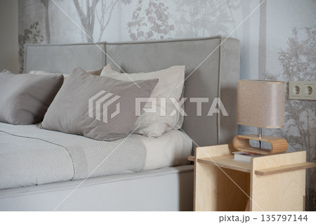 Modern bedroom interior with wooden nightstand and gray pillows Modern bedroom interior with wooden nightstand and gray pillows 135797144