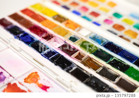 Watercolor pans in white plastic box for painting. Opened paint set for professional watercolor painter on white background. 135797288