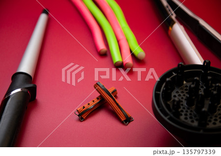 Spreading curlers, hair irons and curling irons on a pink background to create hairstyles. The concept of hairdressing salons, self-care. High quality photo Spreading curlers, hair irons and curling irons on a pink background to create hairstyles. The concept of hairdressing salons, self-care. High quality photo 135797339