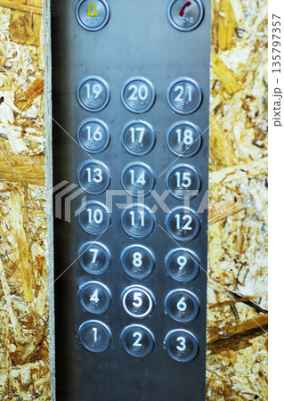Close examination of scratched metal elevator buttons amid dusty renovation environment 135797357