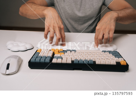 Person placing cloud-shaped wrist rest for ergonomic comfort while using mechanical keyboard and wireless mouse on clean white desk, highlighting modern desk setup for work or gaming. 135797593