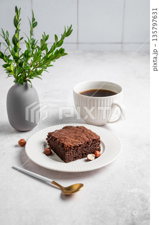 Piece of chocolate brownie on a plate and a cup of espresso coffee on a light background Piece of chocolate brownie on a plate and a cup of espresso coffee on a light background 135797631
