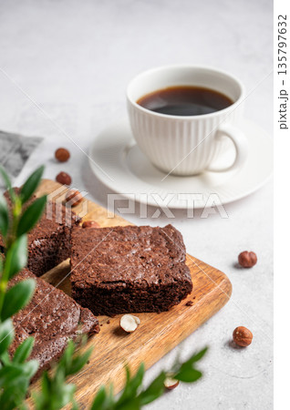 Pieces of chocolate brownie on a wooden board and a cup of espresso coffee on a light background Pieces of chocolate brownie on a wooden board and a cup of espresso coffee on a light background 135797632