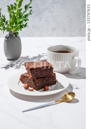 Chocolate brownie on a plate and a cup of espresso coffee on a marble background Chocolate brownie on a plate and a cup of espresso coffee on a marble background 135797633