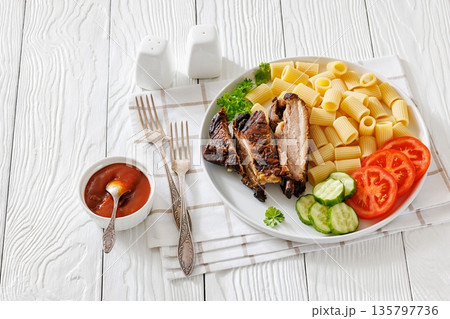 Fried pork ribs with pasta and fresh vegetables 135797736