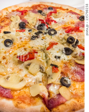 Freshly baked pizza topped with savory ingredients in a cozy setting Freshly baked pizza topped with savory ingredients in a cozy setting 135798158