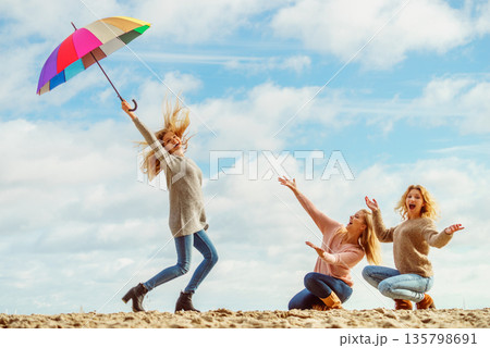 Women holding umbrella having fun with friends Women holding umbrella having fun with friends 135798691