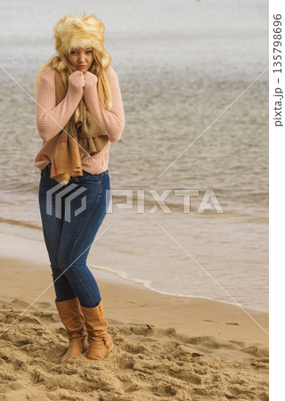 Woman in stylish outfit feeling cold by the sea 135798696