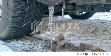 Icicles formed on the underside of the car in winter. Severe frosts and cold weather in Europe. High quality photo 135799104