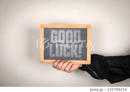 GOOD LUCK Message On Chalkboard Held By Hand Against Neutral Background 135799254