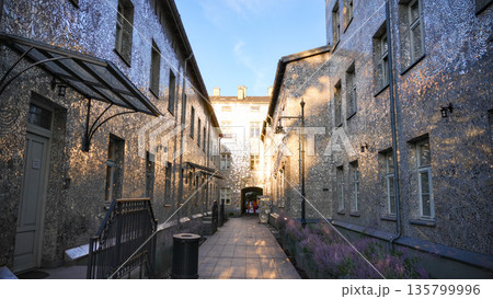 Symmetrical narrow street with stone buildings and warm sunlight in Lodz 135799996