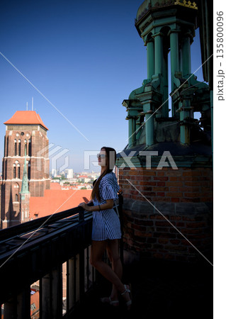 Woman on church rooftop terrace with St Marys Basilica tower and Gdansk Old Town 135800096