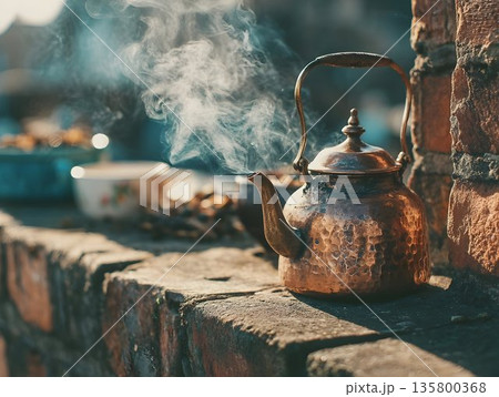 antique metal copper teapot stands on the table and boils, hot steam, tea party antique metal copper teapot stands on the table and boils, hot steam, tea party 135800368