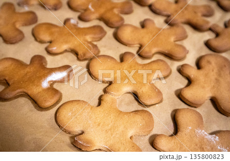 Homemade gingerbread men cookies cooling on baking paper close-up, warm-toned shot. Classic Christmas holiday treats, popular for festive appeal, perfect for seasonal, winter, food-related themes. Homemade gingerbread men cookies cooling on baking paper close-up, warm-toned shot. Classic Christmas holiday treats, popular for festive appeal, perfect for seasonal, winter, food-related themes. 135800823