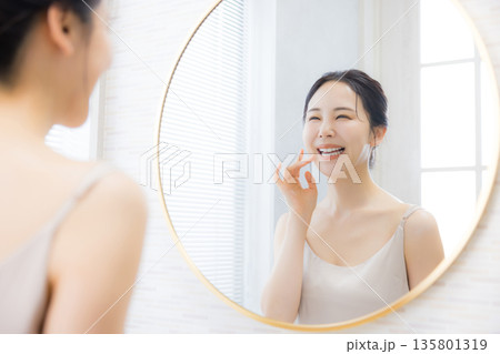 洗面所で鏡を見る若い女性 洗面所で鏡を見る若い女性 135801319