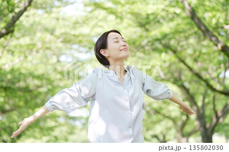 屋外で深呼吸する40代女性 135802030
