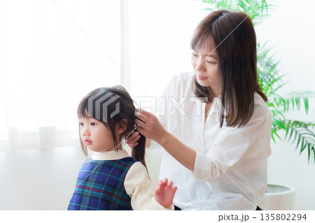 女の子の髪を結ぶお母さん 135802294