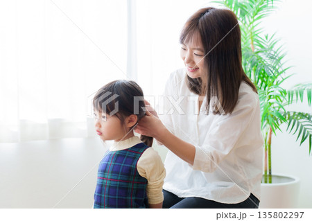 女の子の髪を結ぶお母さん 135802297