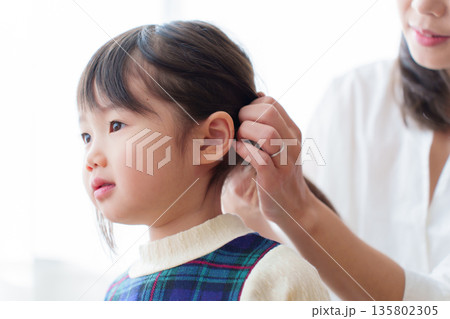 女の子の髪を結ぶお母さん 135802305