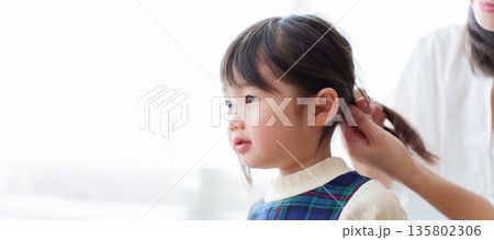 女の子の髪を結ぶお母さん 135802306