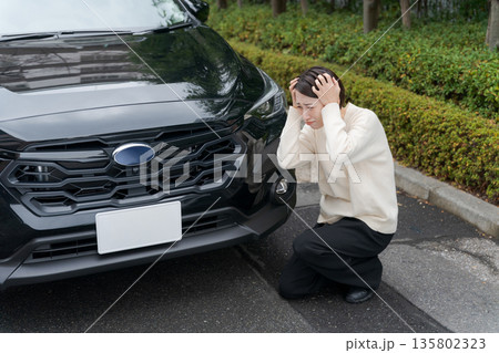 車をぶつけて道にしゃがみ込む女性 車をぶつけて道にしゃがみ込む女性 135802323