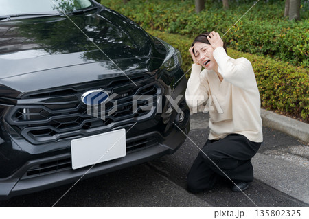 車をぶつけて道にしゃがみ込む女性 車をぶつけて道にしゃがみ込む女性 135802325