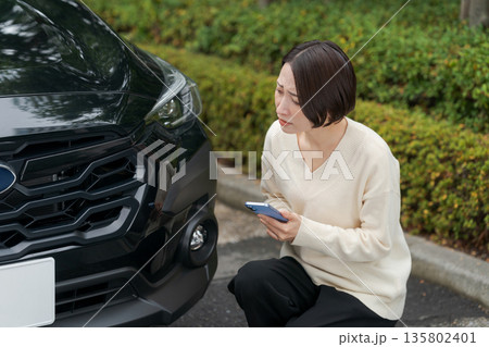 車のトラブルでスマホを操作する女性 135802401