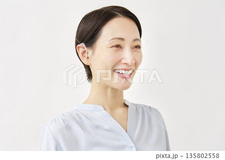 補聴器を使う40代の女性 白背景 補聴器を使う40代の女性 白背景 135802558