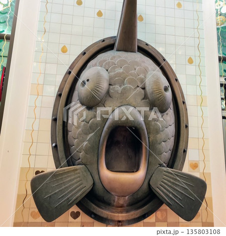 Fish sculpture with exaggerated features, mounted on a tiled wall in Amsterdam 135803108