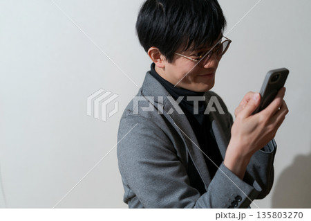 スマホを見る怪しげな男性 スマホを見る怪しげな男性 135803270