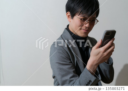 スマホを見る怪しげな男性 スマホを見る怪しげな男性 135803271