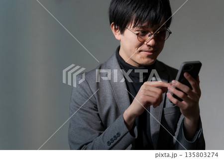 スマホを見る怪しげな男性 スマホを見る怪しげな男性 135803274