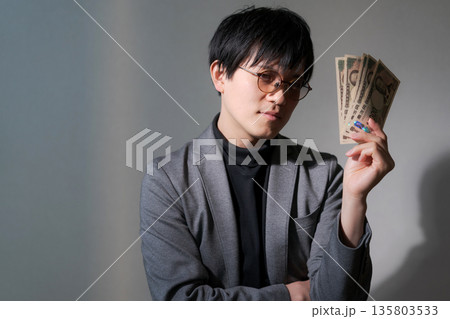 スマホとお金を持つ怪しい男性 スマホとお金を持つ怪しい男性 135803533