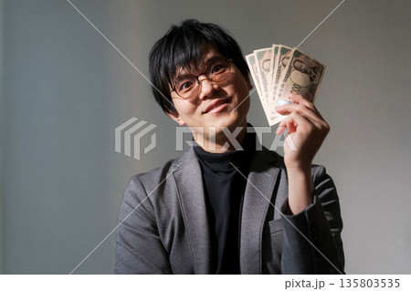 スマホとお金を持つ怪しい男性 スマホとお金を持つ怪しい男性 135803535