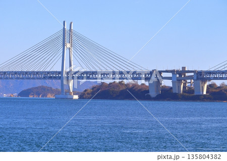 本島から眺める瀬戸大橋内を走行する列車と岩黒島（瀬戸大橋線） 135804382