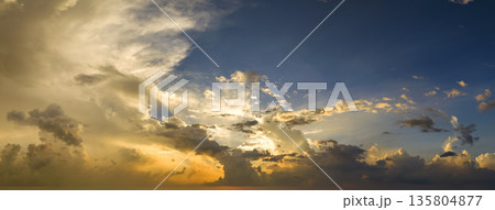 Bright sunset with setting sun behind vivid orange and yellow clouds 135804877