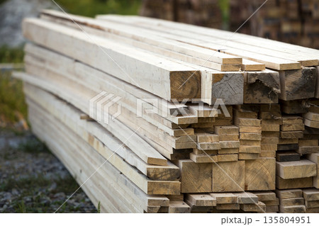 Stack of natural brown uneven rough wooden boards on building site. Industrial timber for carpentry, building, repairing and furniture, lumber material for roofing construction. Stack of natural brown uneven rough wooden boards on building site. Industrial timber for carpentry, building, repairing and furniture, lumber material for roofing construction. 135804951