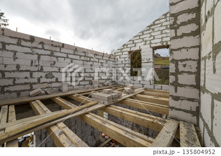 Interior of future cottage, energy saving walls and chimney of large white hollow foam insulation on blue sky and woody hills copy space background. Construction, masonry, modern technology concept. Interior of future cottage, energy saving walls and chimney of large white hollow foam insulation on blue sky and woody hills copy space background. Construction, masonry, modern technology concept. 135804952
